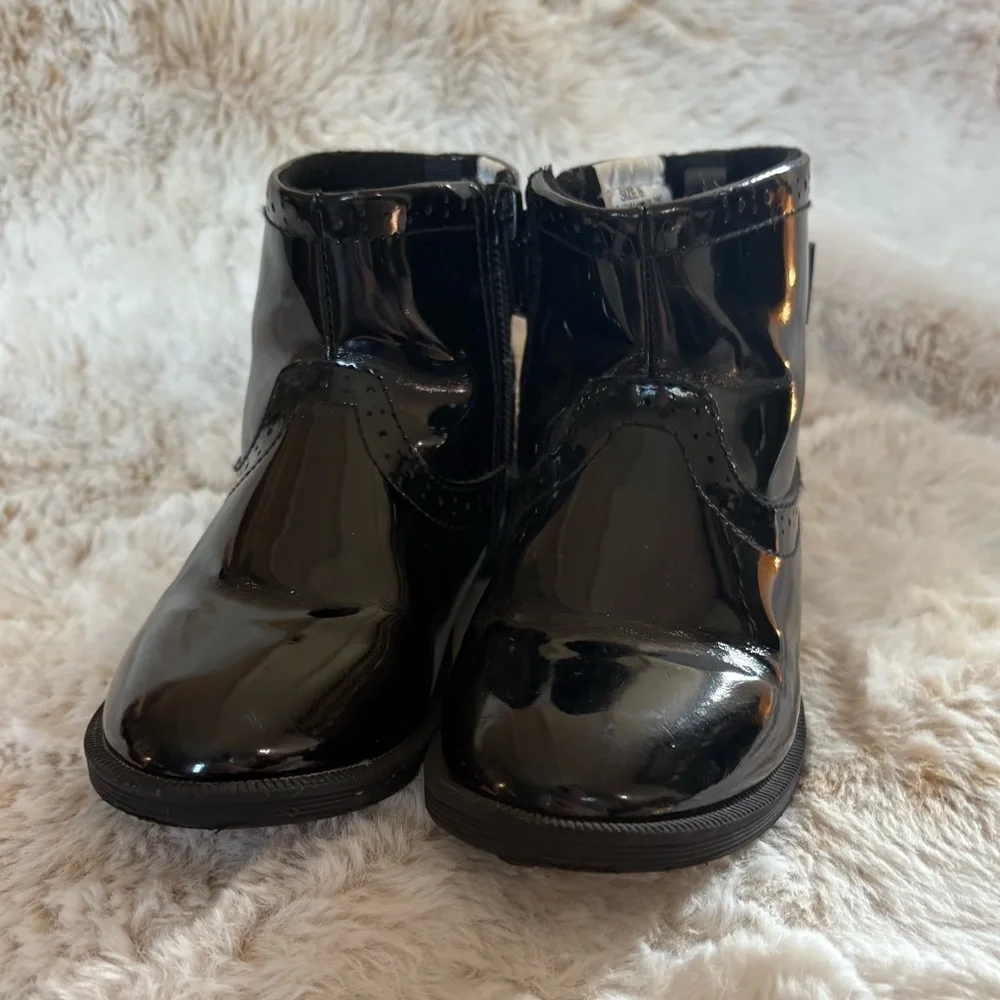 Little girls glossy black boots with bow on the back.
